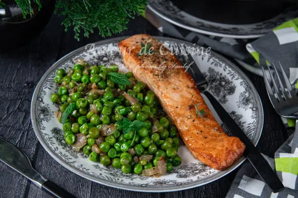Filet de saumon poêlé servi avec une poêlée de petits pois et oignons, garnie de menthe fraîche. Une recette simple et savoureuse.
