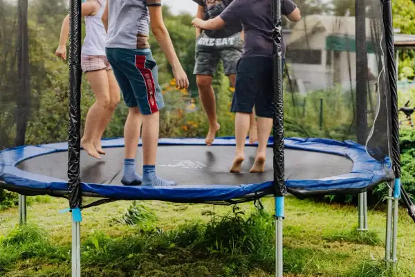 Dzieci skaczą na trampolinie, świetna zabawa i aktywność fizyczna. Czy trampolina jest zdrowa dla dzieci? Tak, rozwija koordynację i kondycję.