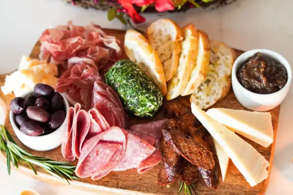 Planche apéro gourmande : charcuteries fines, fromages variés, olives, pain grillé, confiture de figues et fromage frais aux herbes. Une belle idée pour un moment convivial.