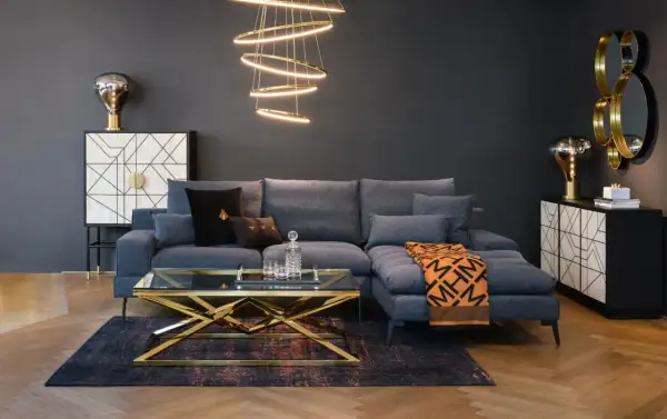 Nowoczesny, **soft loft salon** z szarą sofą, złotym stolikiem kawowym i designerską lampą.