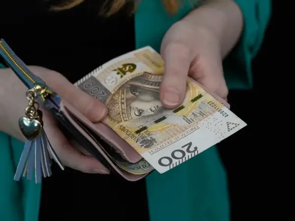 Ręce trzymają portfel z banknotami 200 zł. Ile wynosi rodzinne wsparcie?