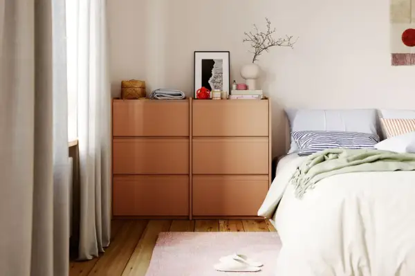 Modernes schlafzimmer design mit orangefarbenen Kommoden, einem Bett mit gestreiften Kissen und einer grünen Decke.