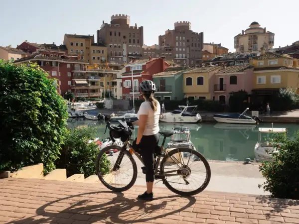 Ciclista en un puerto con casas de colores y barcos. Perfecta para descubrir las **rutas bici Valencia**.