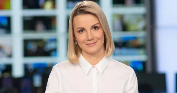 Joanna Dunikowska-Paź, znana z Wikipedii, w białej koszuli, z kolczykami, na tle ekranów.