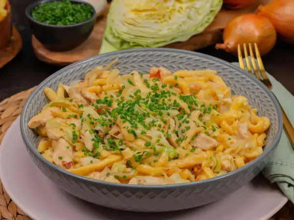 Herzhafte Spätzle mit Hähnchen und Spitzkohl, garniert mit Schnittlauch. Ein leckeres Gericht, das zeigt, wie vielseitig Spitzkohl Rezepte sein können.