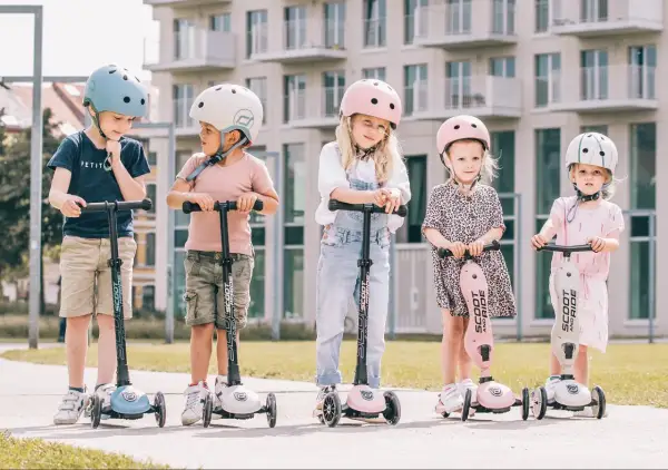Fizjoterapeuta poleca Scoot and Ride dla dzieci. Pięcioro maluchów w kaskach na hulajnogach, gotowych do zabawy.