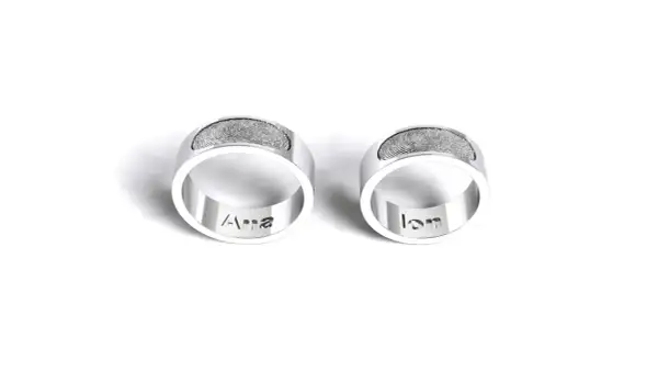 Dos anillos de plata grabados con huellas dactilares y nombres: "Ana" y "Ian". Un símbolo de amor eterno para rodear el dedo.