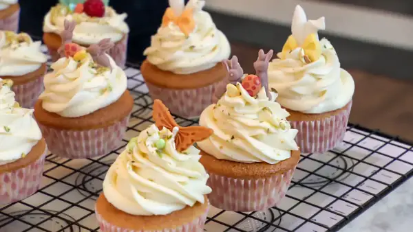 Zarte Vanille Cupcakes mit cremiger Glasur, verziert mit süßen Osterhasen und bunten Eiern. Ein Fest für die Augen und den Gaumen!