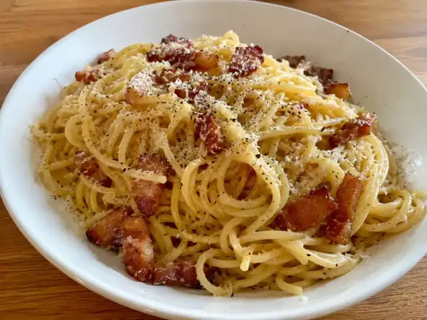 En krämig carbonara med pancetta, toppad med riven ost och svartpeppar. En klassisk italiensk rätt som ser utsökt ut.
