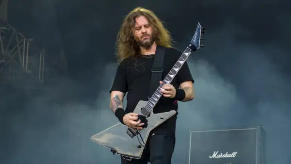 Charyzmatyczny gitarzysta rockowy z długimi włosami, grający na czarnej gitarze typu explorer. Jeden z wielu utalentowanych polskich gitarzystów rockowych.