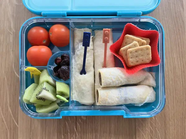 Kolorowe śniadaniówkowe pudełko dla dzieci: pomidorki, kiwi, suszone śliwki, naleśniki z czekoladą i ciasteczka. Idealne na drugie śniadanie!