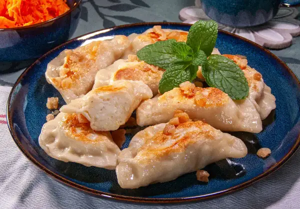 Pyszne pierogi ruskie przepis babci, okraszone skwarkami i udekorowane miętą.