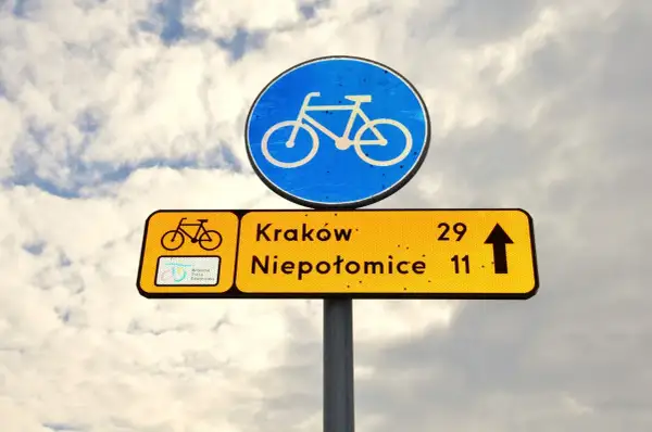 Znak drogowy informuje, że kiedy rowerzysta ma pierwszeństwo, kieruje się na Kraków (29 km) i Niepołomice (11 km).