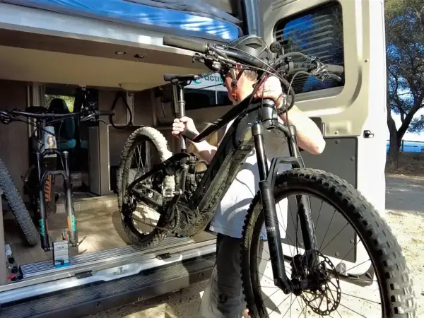 Hombre cargando una bici eléctrica en una furgoneta. Así es como llevar la bici dentro de la furgoneta para tus aventuras.