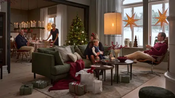 En familj samlas för en mysig jul. Julgranen är klädd, presenter ligger utspridda och ljusen lyser upp rummet.