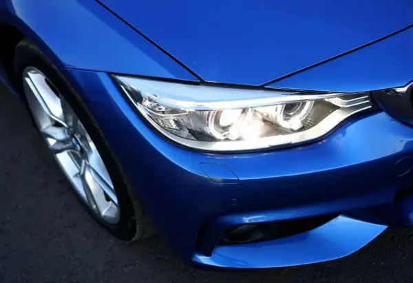 Gros plan sur le phare d'une voiture bleue éclatante, prêt à illuminer la route.