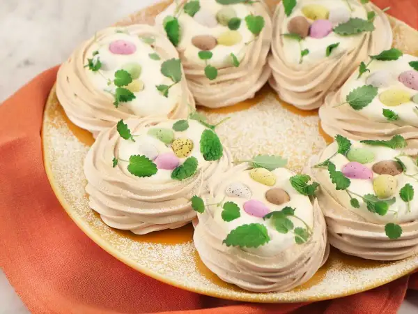 Små marängbottnar fyllda med grädde och dekorerade med färgglada påskägg och mynta. En perfekt pavlova påsk-dessert!