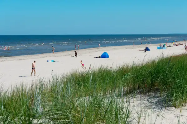 Menschen genießen einen sonnigen Tag am Strand der Ostsee. Nach der Fahrt mit dem Zug von Berlin ist dies eine willkommene Erfrischung.