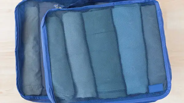 Två blå packpåsar med rullade kläder. Ett perfekt **pile material** för organiserad packning.