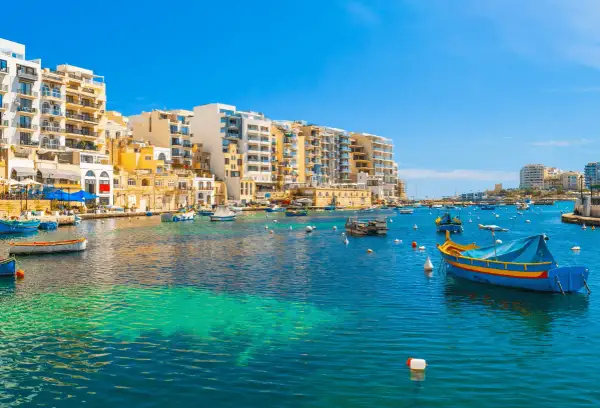 Malta: kolorowe łodzie kołyszą się na turkusowej wodzie, a w tle piętrzą się białe budynki. Idealne miejsce, by poczuć śródziemnomorski klimat i wydać ostatnią malta waluta.