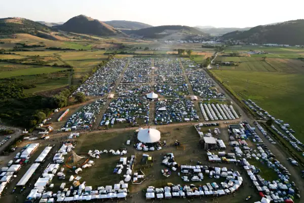 Vasto accampamento di tende e camper per il festival celtico Montelago, immerso in un paesaggio collinare verdeggiante.