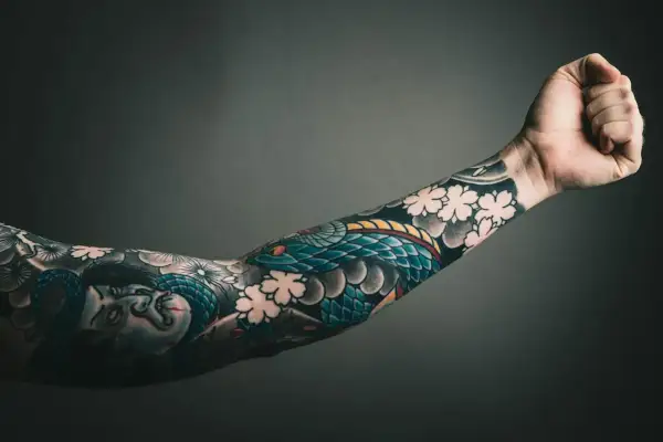 Ein Arm mit einem detaillierten Tattoo-Sleeve, das eine Schlange und Kirschblüten zeigt. Perfekt, um Ideen für ein eigenes tattoo sleeve zusammenstellen zu sammeln.