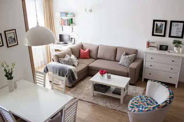 Przytulny salon z narożnikiem, stołem i biurkiem. Układ mieszkań w bloku z wielkiej płyty zaaranżowany na nowo.