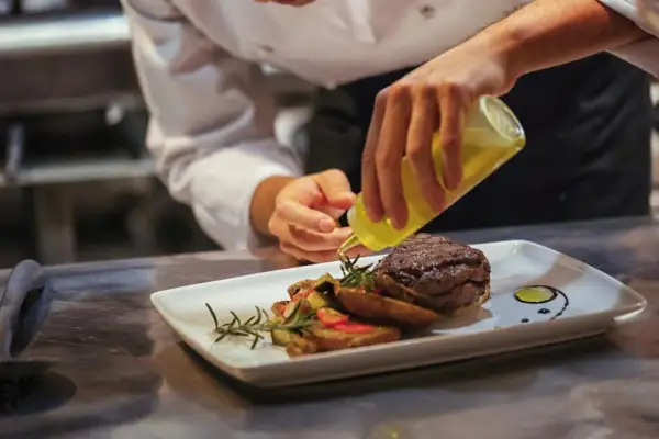 Chef finaliza plato de carne con guarnición. ¿Cuánto gana un cocinero en España? La pasión por la cocina se refleja en cada detalle.