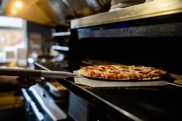 Piec z pizzą na łopacie, gotową do wyjęcia.