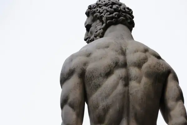 Dos des dieux Zeus, sculpture d'un homme musclé vu de dos, le ciel blanc en arrière-plan.