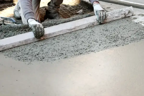Pracownik wyrównuje świeży beton, przygotowując podłogę garażu. Dobry jaki beton na wylewkę do garażu to klucz do trwałej posadzki.