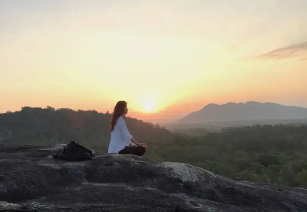 Mujer meditando al amanecer, buscando el equilibrio yin yang en la naturaleza.