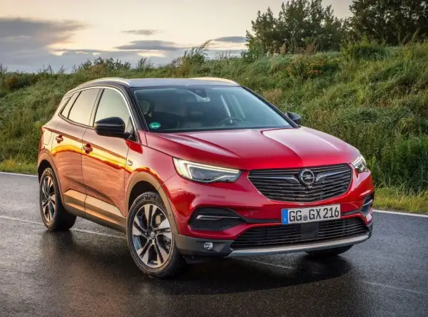 Czerwony Opel Grandland X na mokrej drodze. Wiele pozytywnych opinii o tym modelu.