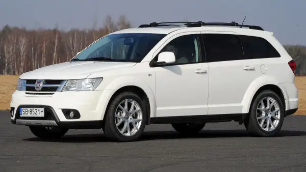 Biały fiat 7 osobowy z relingami na dachu, gotowy na rodzinną podróż.