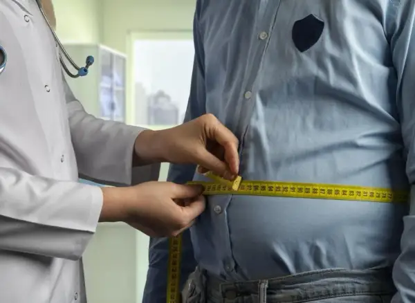Un médecin mesure le tour de taille d'un homme. Une femme de 50 ans pourrait avoir un tour de taille similaire.