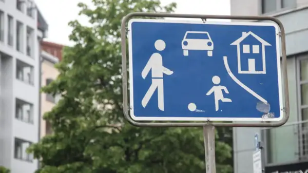Zeichen 325.1: Fußgängerzone mit spielenden Kindern und Autos. Ein Haus symbolisiert Wohngebiet.