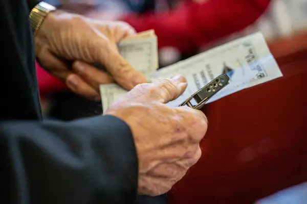 Dłonie trzymające bilety na pociąg, pokazujące, jak kupić bilet na pociąg w Norwegii.