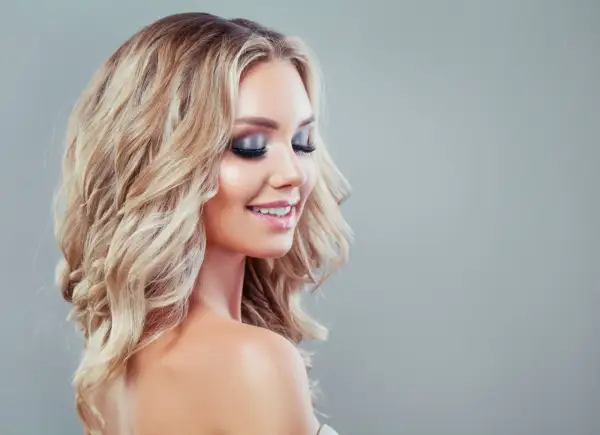 Blondynka z falowanymi włosami i olśniewającym makijażem wieczorowym, idealnym na specjalne okazje.