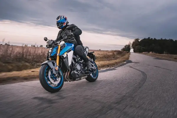 Motocyklista w kasku z brytyjską flagą pokonuje zakręt na drodze, doświadczając zjawiska shimmy.