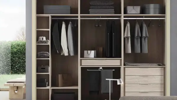 Un armario moderno y funcional, ideal para quienes buscan cómo diseñar un armario con estilo. Ropa colgada, cajones y estantes organizados.