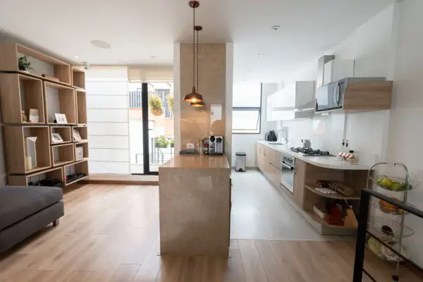 Un tabique de cocina semiabierta al salón crea un espacio moderno y funcional.