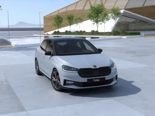 Nowa Skoda Fabia 2026 w jasnym kolorze z czarnym dachem, zaparkowana przed nowoczesnym budynkiem.