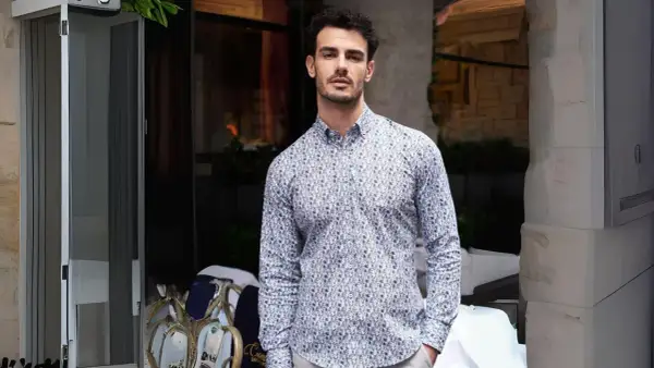 Uomo con camicie di tendenza uomo con fantasia astratta, in piedi all'esterno di un locale.