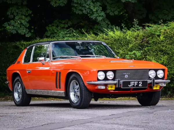 En orange Jensen Interceptor från 70-talet, en klassisk bil med en tidlös design, parkerad utomhus.