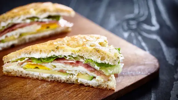 Tramezzini gourmet con prosciutto, uovo, avocado e lattuga su pane soffice. Un'idea per ricette veloci e gustose.