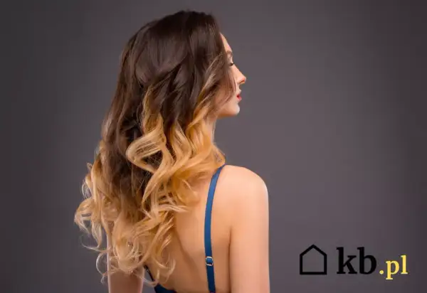 Kobieta z falowanymi włosami w stylu ombre, od ciemnego brązu po jasny blond.