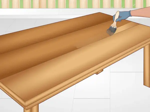 Applying a clear coat to a DIY table. The wooden surface is being brushed with a clear finish, enhancing its natural grain.
