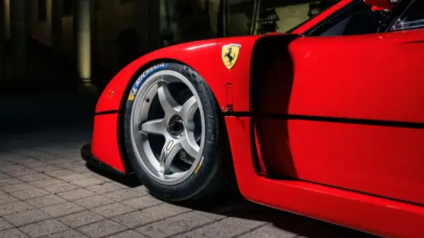 En röd fransk sportbil, en ikonisk Ferrari F40, med sitt legendariska häst-emblem och Michelin-däck.