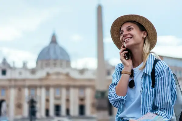 Uśmiechnięta turystka w Rzymie, ciesząca się rozmową przez telefon dzięki internetowi w roamingu.