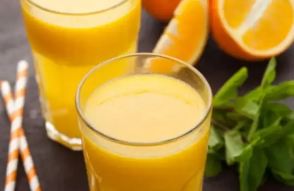 Dwa szklanki świeżego soku pomarańczowego, plasterki pomarańczy i listki mięty. Pyszny napój, który nie ma zbyt wielu pomarańcza kcal.